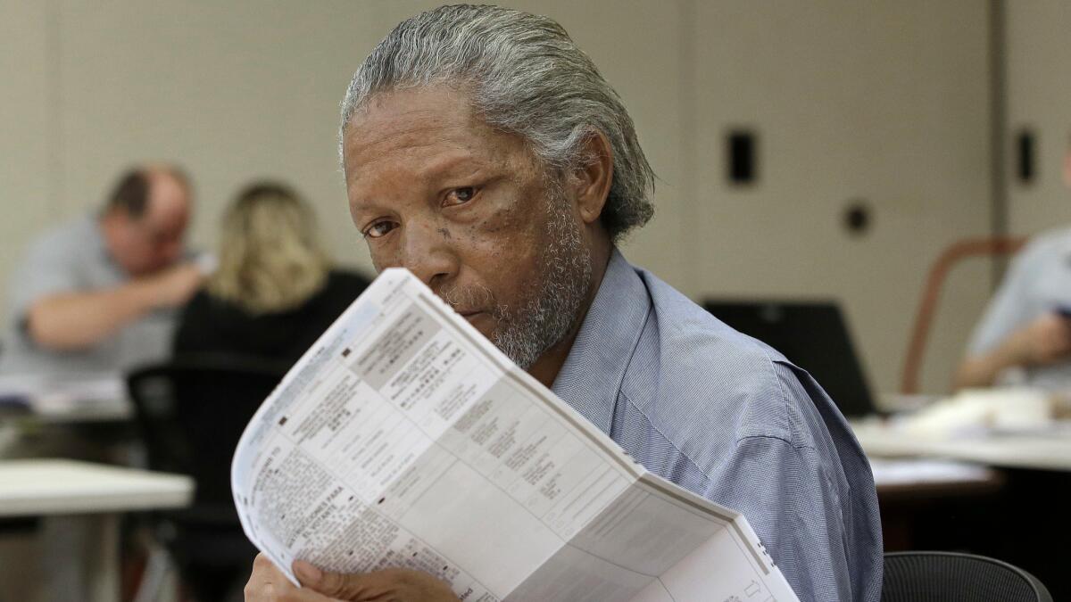 Keith Caston, a temporary worker at the Sacramento County Registrar of Voters office, inspects a mail-in ballot before it is counted on June 10.