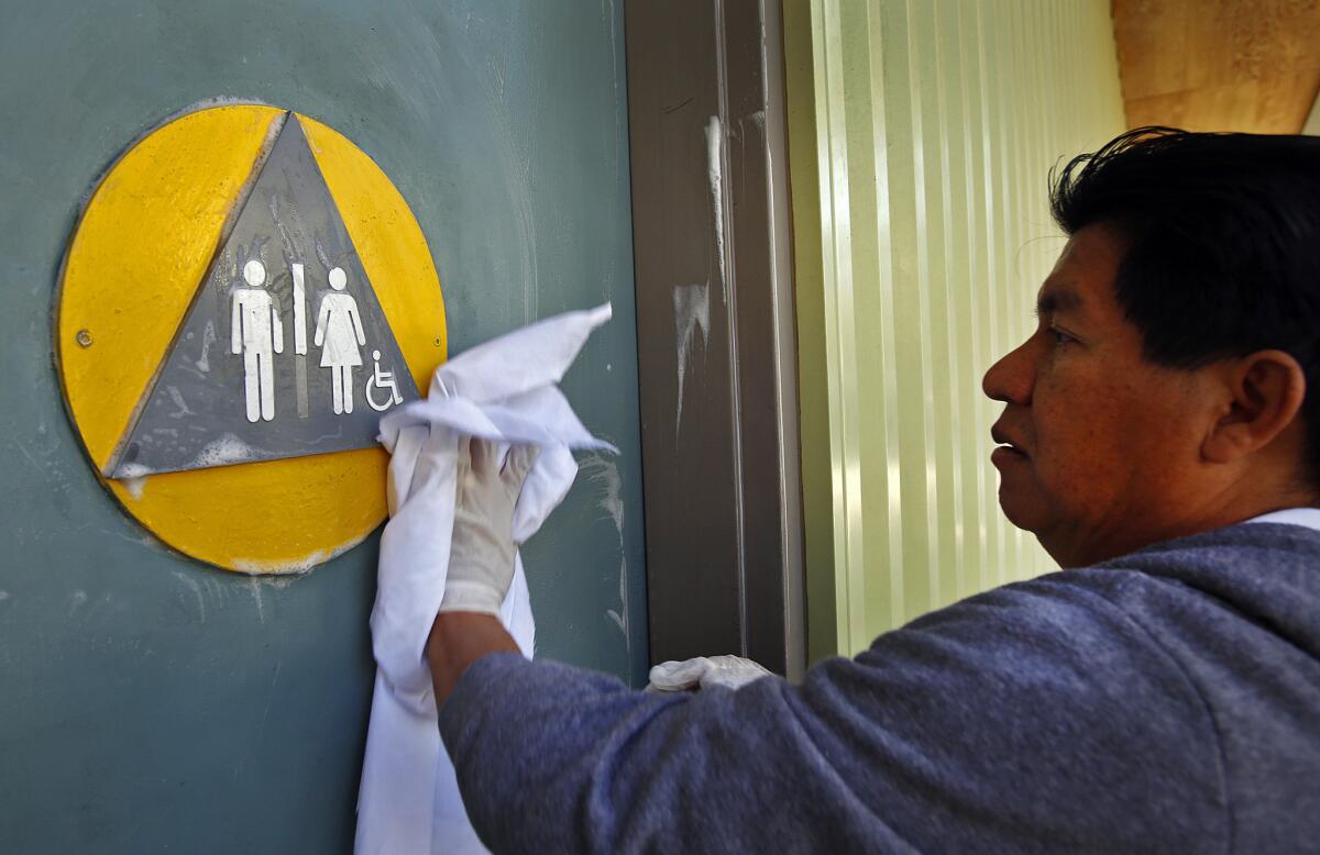 Edgar Lopez, a West Hollywood maintenance worker, cleans the doors to the restroom at Plummer Park last year, months before city-owned facilities and businesses were required to make single-stall restrooms gender-neutral.