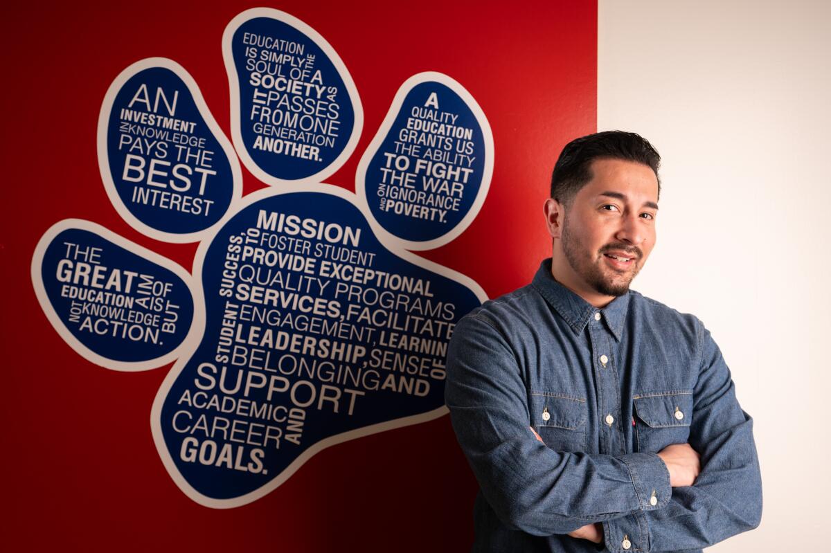 A man in a blue shirt stands next to a paw-shaped diagram on a red wall