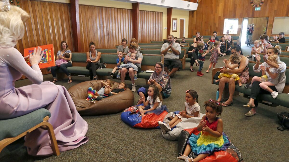 Parents and children applaud after listening to drag queen Autumn Rose read children’s stories at Fairview Community Church in Costa Mesa on Wednesday.