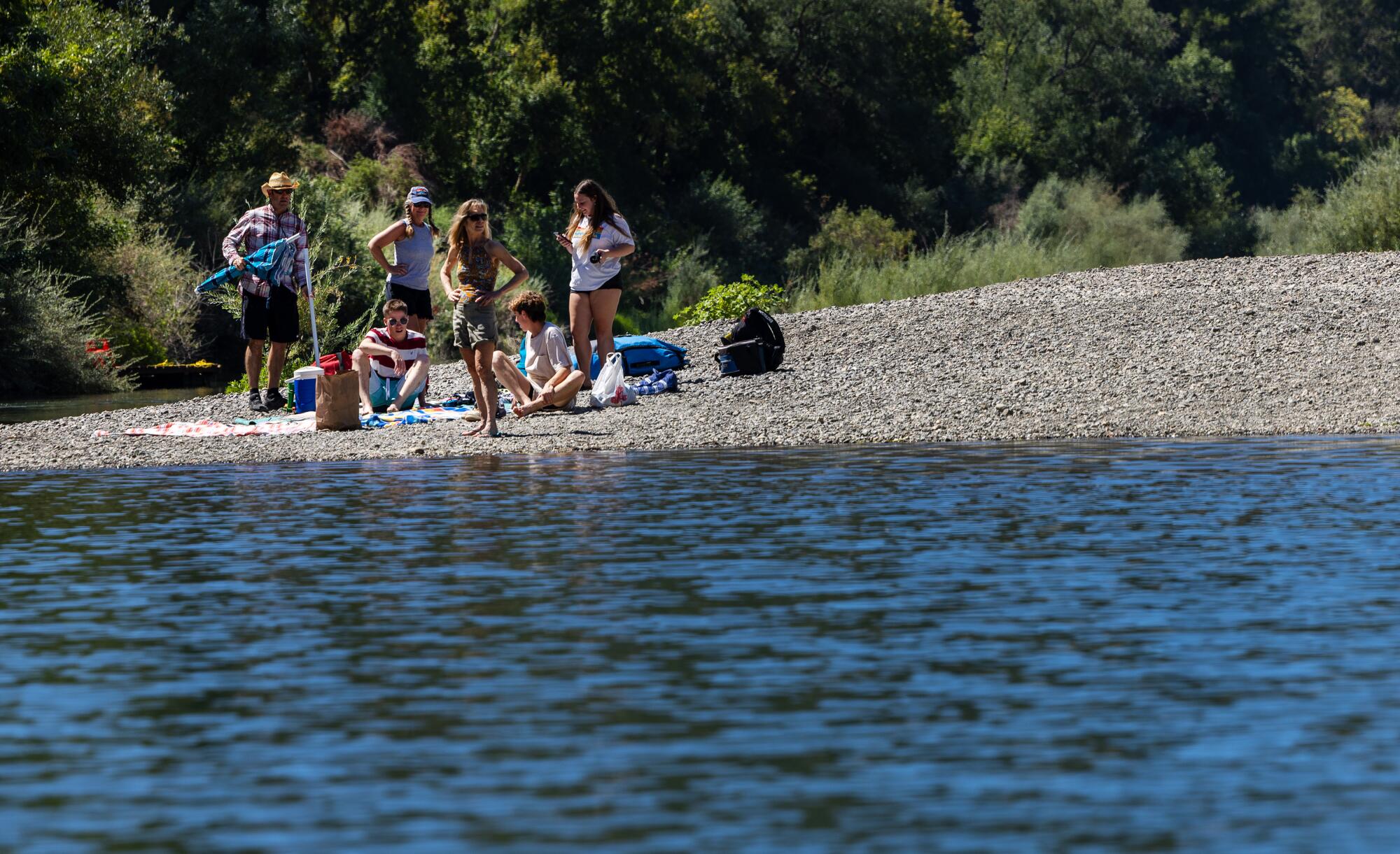 Visitors set out blankets and umbrellas on the Russian River shoreline.