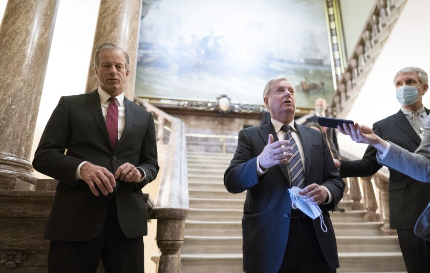 Senate Minority Whip John Thune, R-S.D., left, and Sen. Lindsey Graham, R-S.C., pause outside the Senate chamber to talk with reporters during a delay in work on the Democrats' $1.9 trillion COVID-19 relief bill, at the Capitol in Washington, Friday, March 5, 2021. (AP Photo/J. Scott Applewhite)