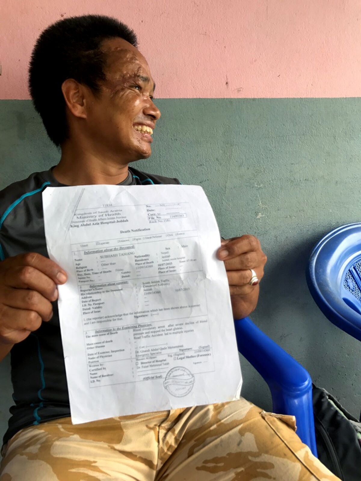 Subash Tamang holds his own death certificate from Saudi Arabia, sitting on his porch in Laxmimarga, Nepal.