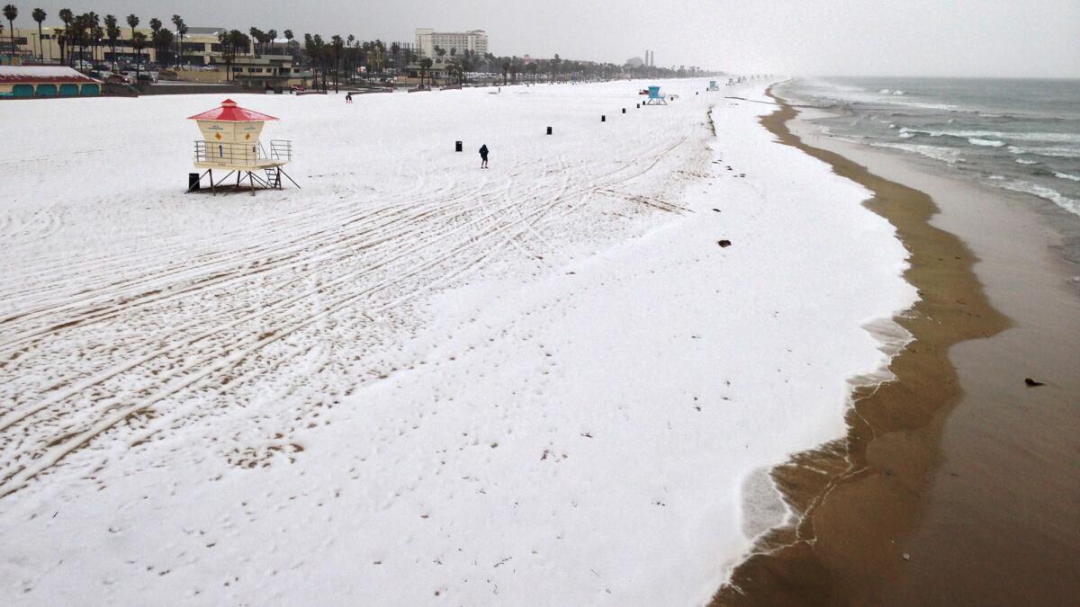 A blanket of hail covers the beach just north of the Huntington Beach Pier on Monday morning.