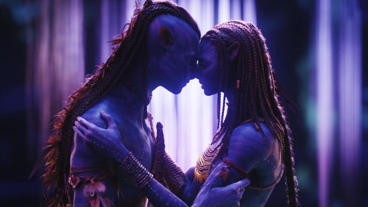 Two blue human-like creatures hold each other and touch foreheads in a movie scene.