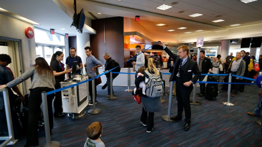 Passengers line up to board an American Airlines flight at Los Angeles International Airport. The airline will board "basic economy" passengers last, starting March 1.