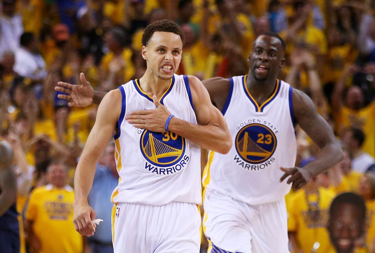 Warriors guard Stephen Curry (30) and forward Draymond Green (23) celebrate as they pull ahead of the Cavaliers in the fourth quarter of Game 5.