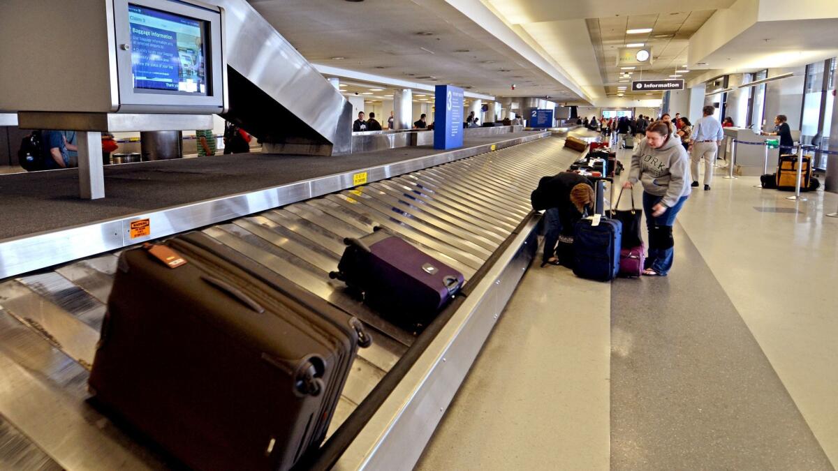 Passengers pick up their luggage at Terminal 7 at Los Angeles International Airport. JetBlue has increased checked bag fees to $30 for passengers who buy the carrier's most inexpensive tickets.