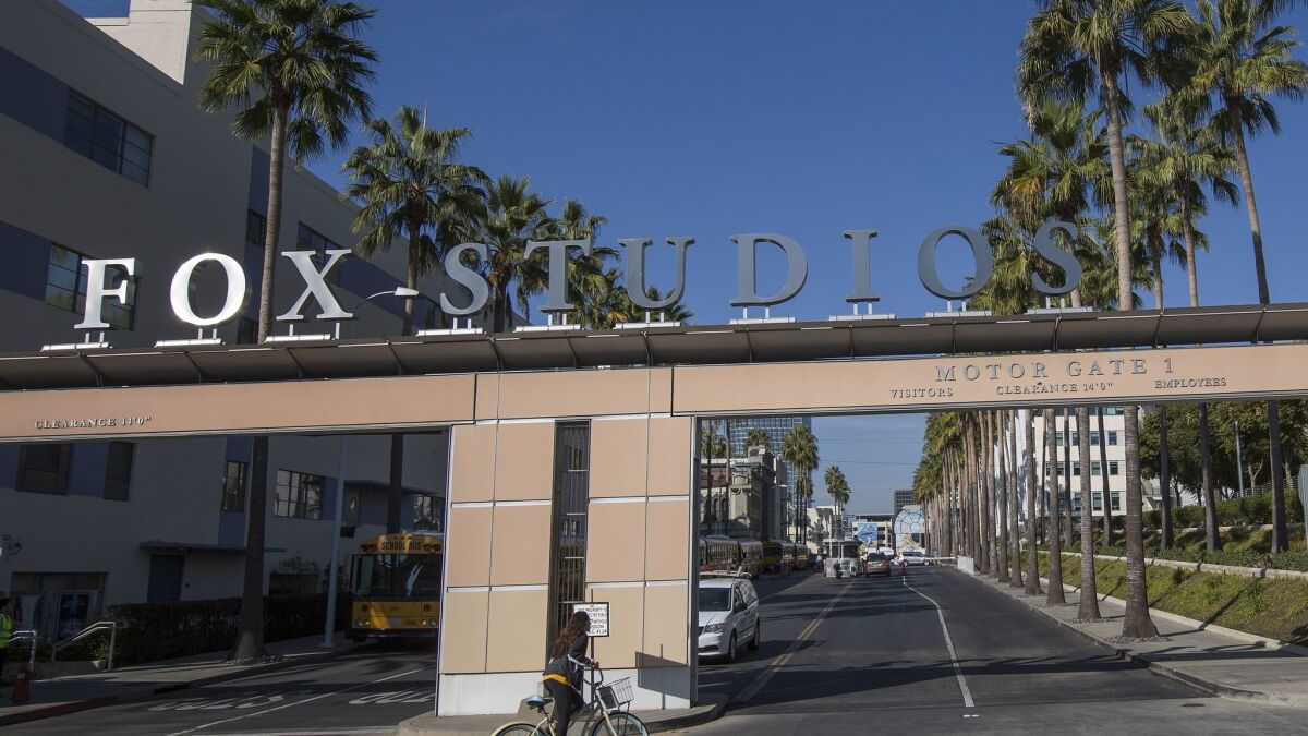 A bicyclist rides through the main entrance to Fox Studios after the Walt Disney Company announced that it will acquire 21st Century Fox on Dec. 14 in Los Angeles.