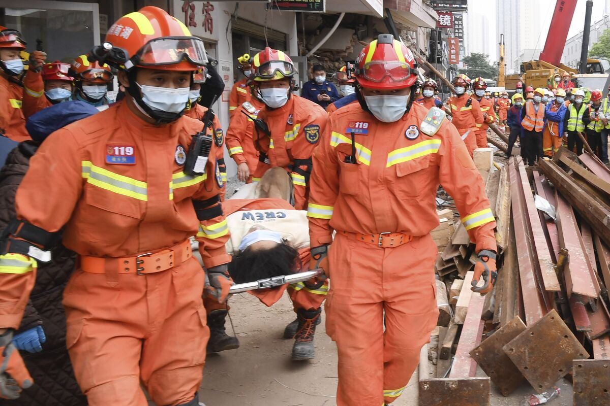 In this photo released by Xinhua News Agency, rescuers evacuate a woman pulled alive from a collapsed building in Changsha, central China's Hunan Province, May 1, 2022. The woman was rescued Sunday from the rubble of a building in central China more than 50 hours after it collapsed, leaving dozens trapped or missing, state media said. (Shen Hong/Xinhua via AP)
