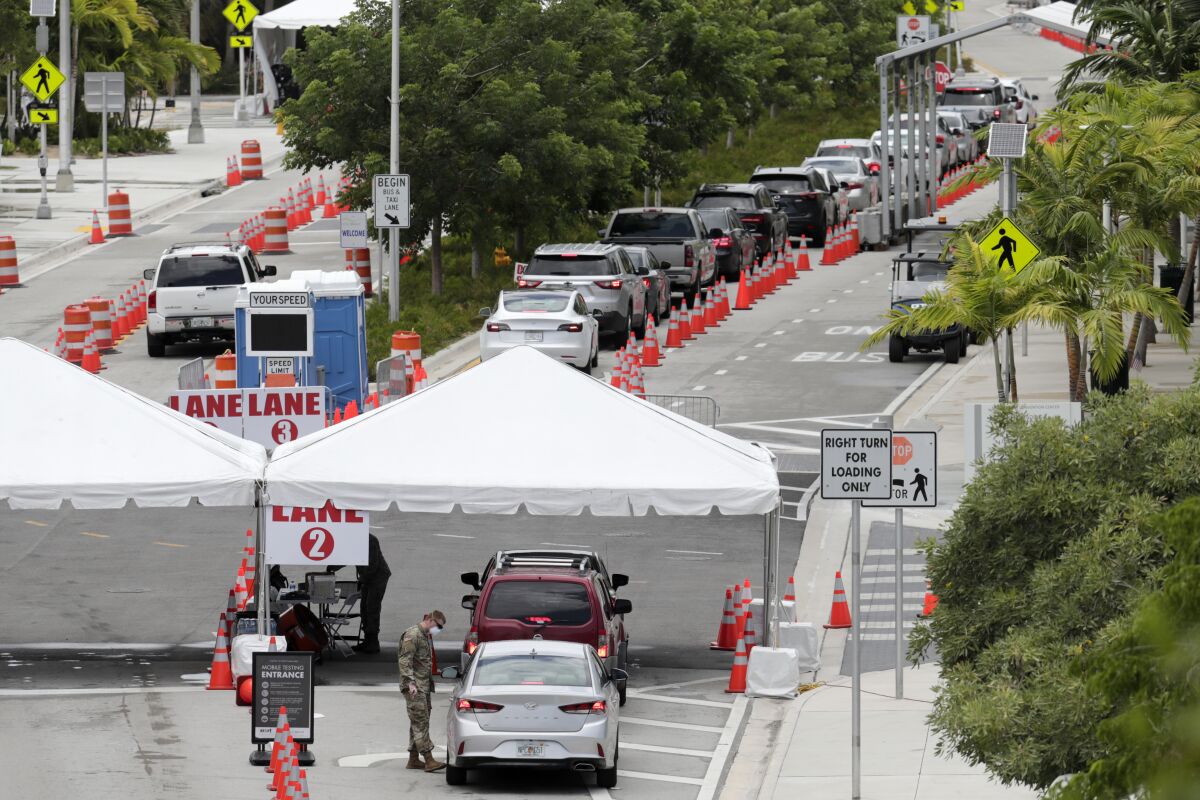 FILE - In this Sunday, July 12, 2020, vehicles wait in line at a COVID-19 testing site at the Miami Beach Convention Center during the coronavirus pandemic in Miami Beach, Fla. As coronavirus cases surge in hard-hit Florida, so do the turnaround times for test results. (AP Photo/Lynne Sladky, File)