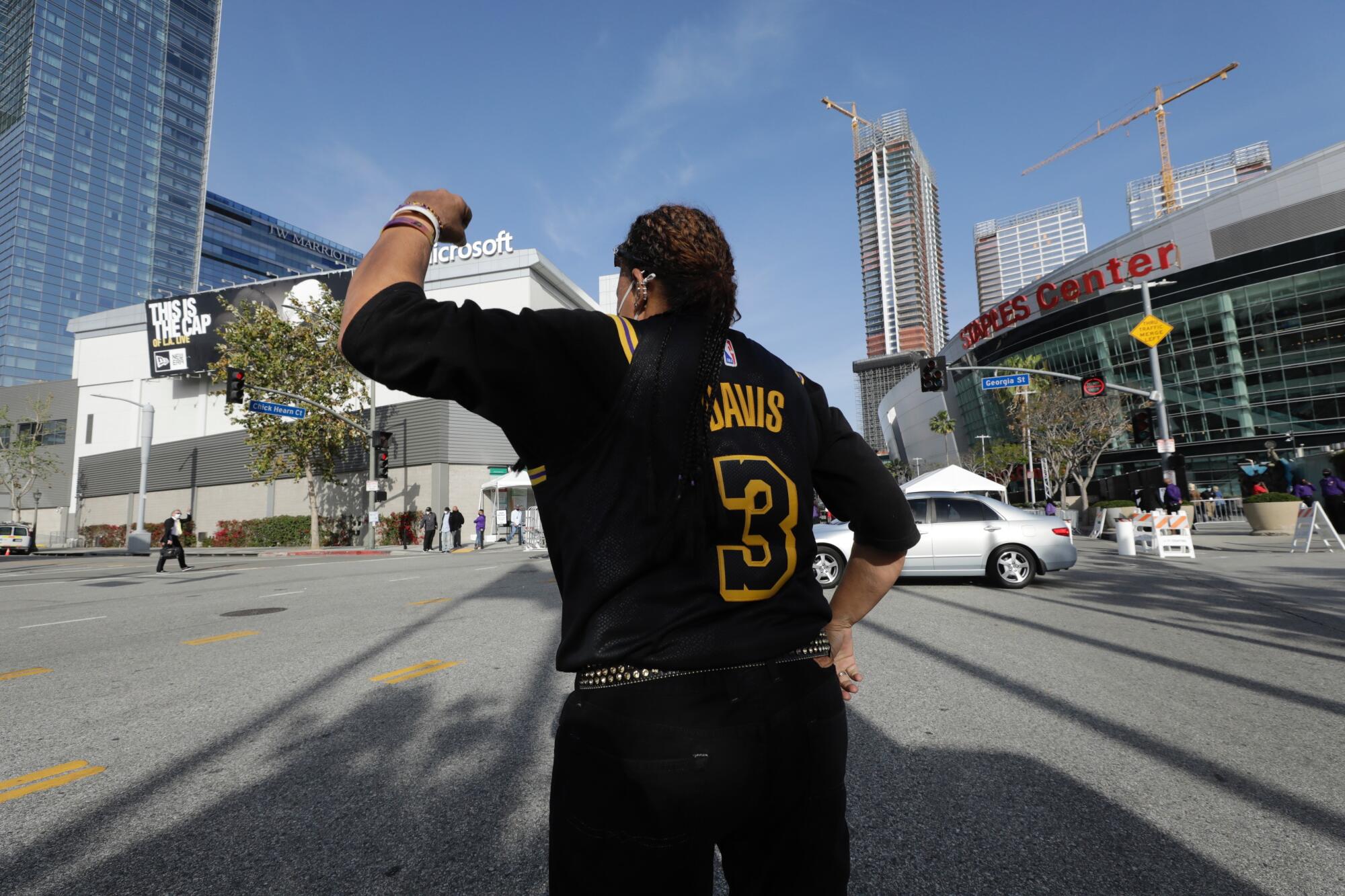 Lakers fan Desiree Engle cheers on announcer Bill Macdonald (crossing street) as he arrives at Staples Center on Thursday.