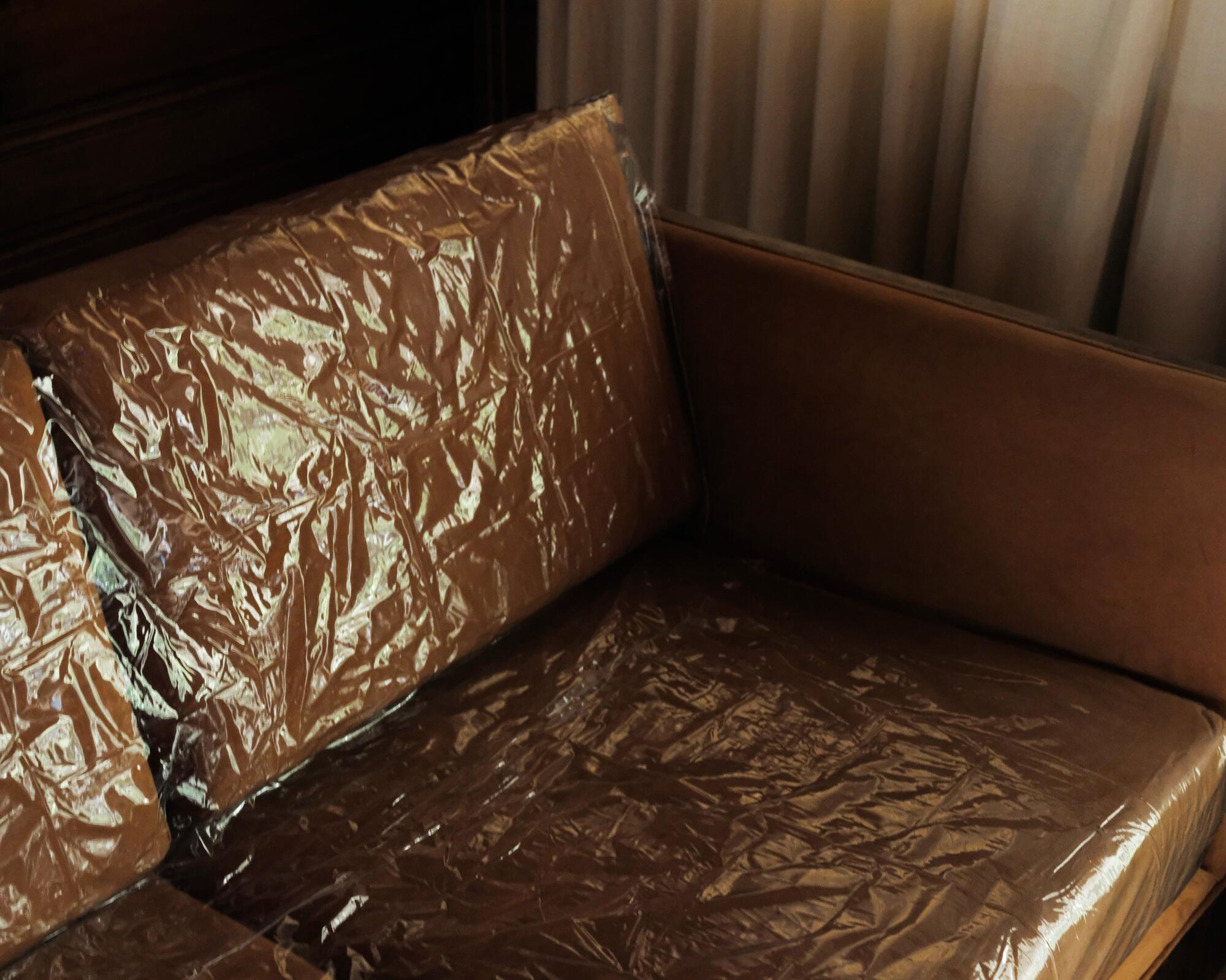 A close-up photo of a plastic-covered couch, the light hitting the wrinkles.