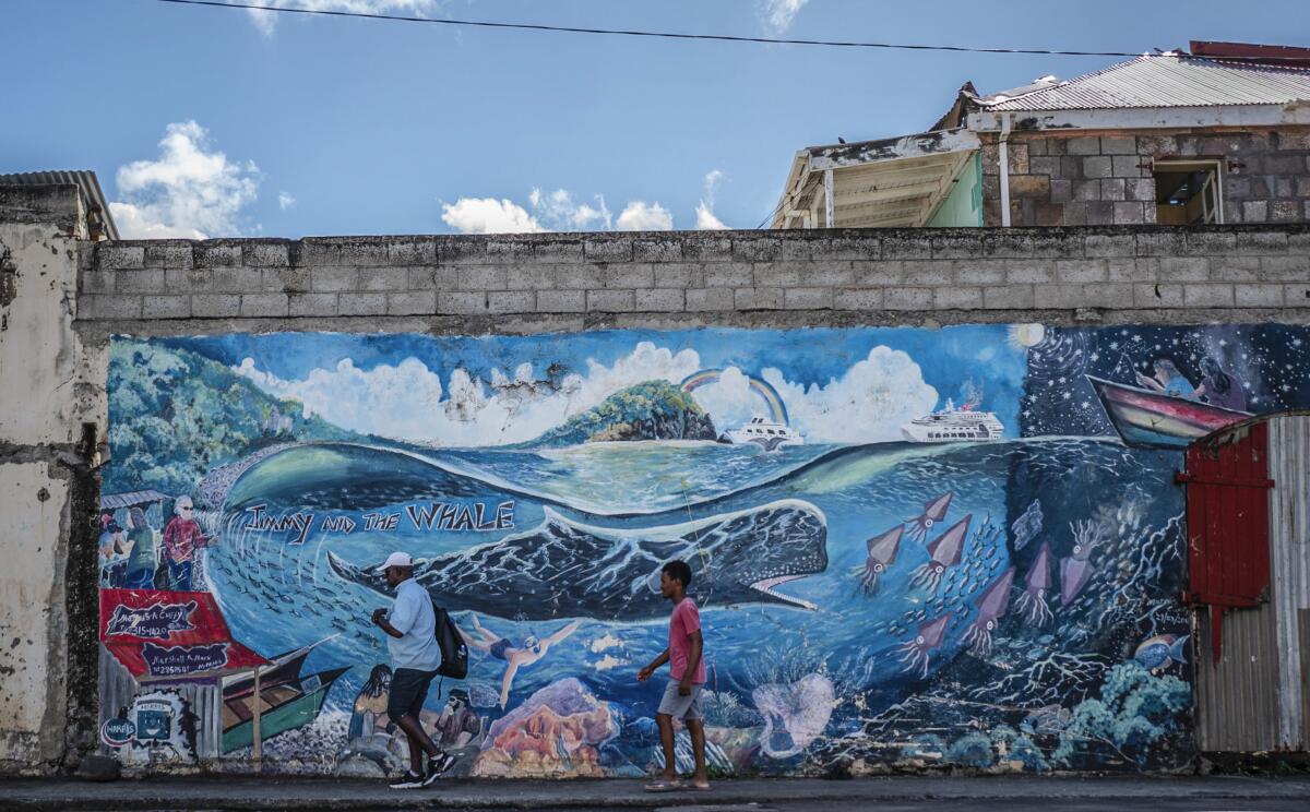 People walk past a mural of a whale.