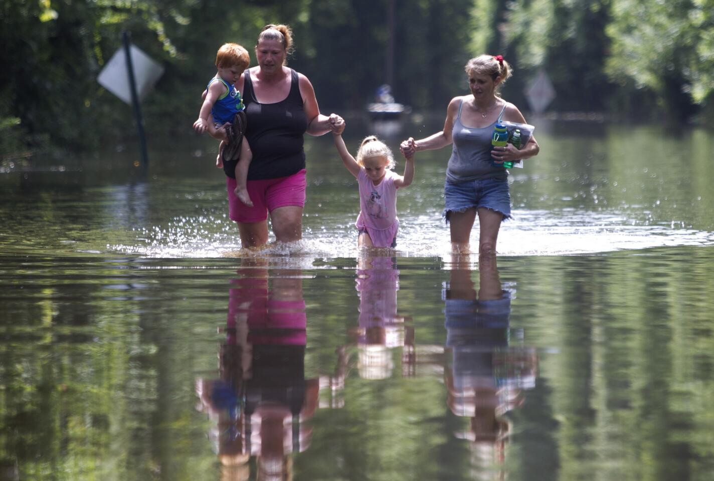 Residents of the Knights Forest subdivision wade through water as they leave their homes in Hardin, Texas. Heavy rain, coupled with increased water released from the Lake Livingston Dam, has caused the Trinity River to flood several neighborhoods near the river.