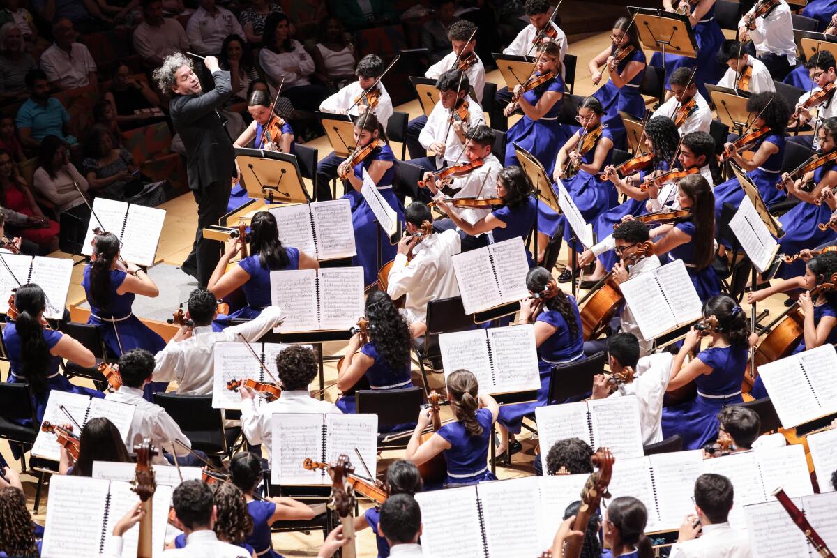 Gustavo Dudamel, with his baton in the air, conducts the National Children's Symphony of Venezuela.