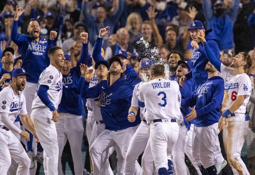 Dodgers celebrate and look at Chris Taylor's thrown helmet as he approaches home plate.