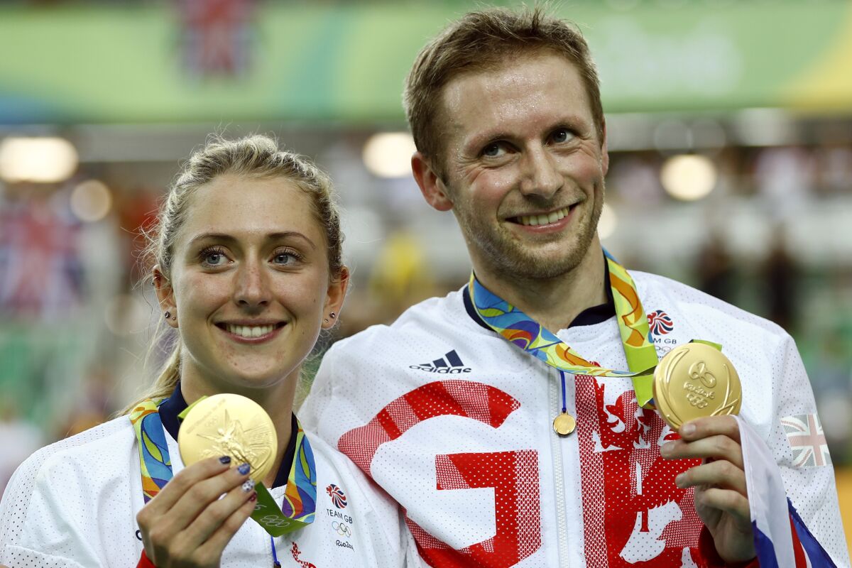 FILE - Laura Trott, left, and her fiance Jason Kenny, both of Britain, pose with their gold medals at the Rio Olympic Velodrome during the 2016 Summer Olympics in Rio de Janeiro, Brazil, in this Tuesday, Aug. 16, 2016, file photo. Britain is hoping to back up consecutive dominant performances in Olympic cycling at the Tokyo Games next month, though much has changed since Rio. Allegations of bullying, sexism and discrimination along with doping charges leveled at its ex-chief doctor have led to leadership changes at British Cycling. Still, such riders at the husband-wife track duo of Jason and Laura Kenny and youngsters such as Tao Geoghegan Hart have the British team eyeing more gold in Japan. (AP Photo/Patrick Semansky, File)
