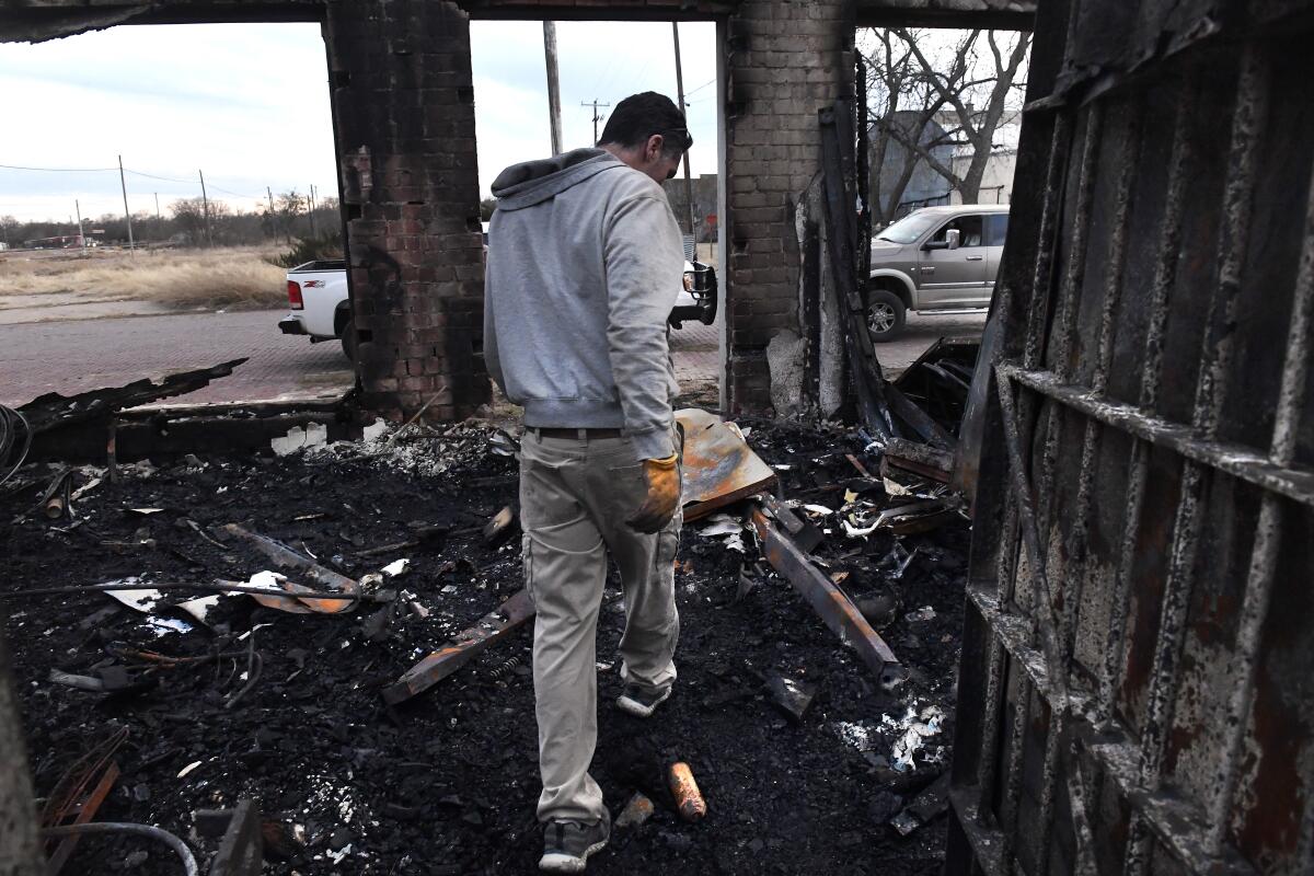 Jared Calvert walks through burnt debris.