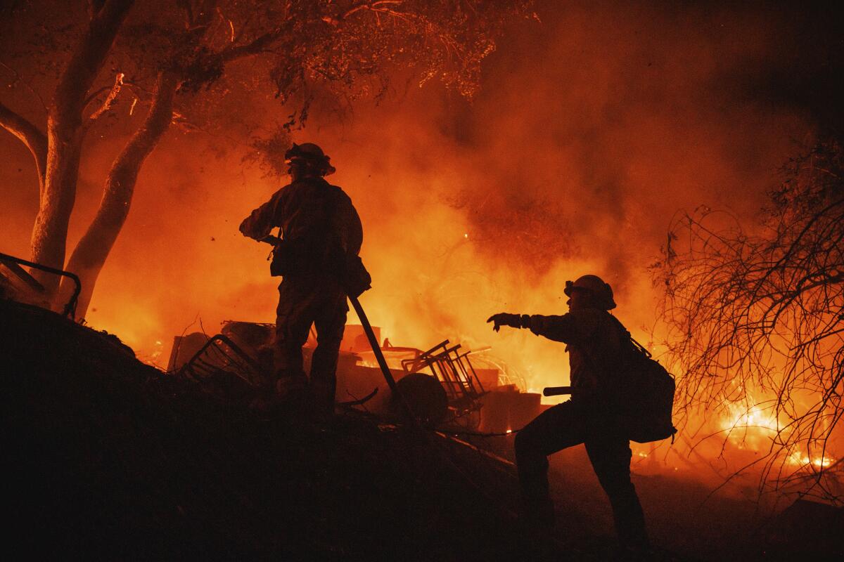 Firefighters are silhouetted against flames as they battle a large fire