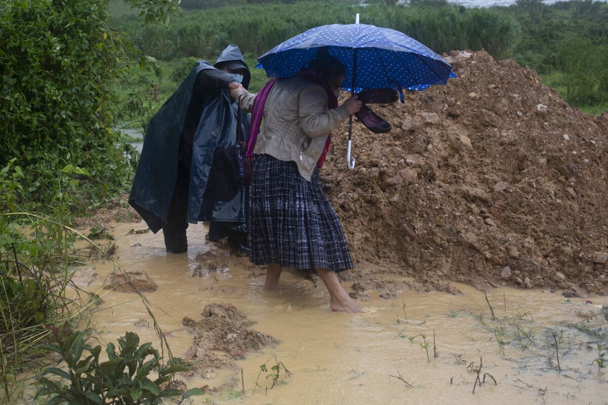 People try to walk around a road blocked by a landslide caused by Hurricane Eta in Purulha, Guatemala, on Friday
