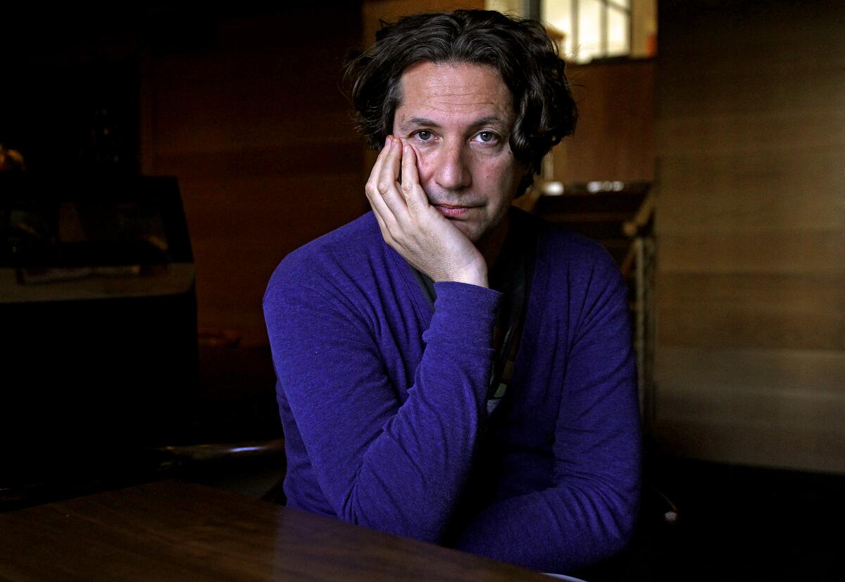 Jonathan Glazer rests his chin in his hand for a portrait.
