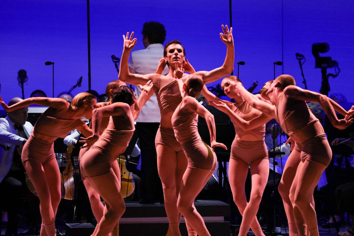 A group of dancers perform before an orchestra.