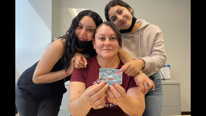 Patricia muestra orgullosa su tarjeta verde a lado de sus hijas.
