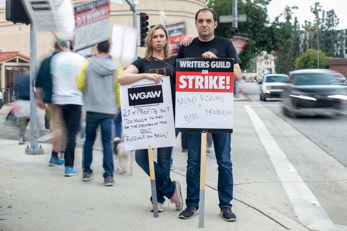 A woman and a man stand with picket signs. 
