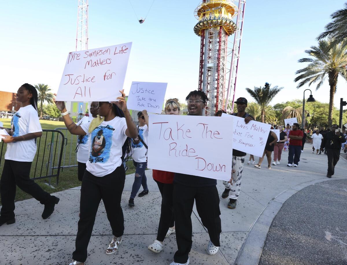 FILE - Family and supporters of Tyre Sampson march and hold signs outside the Orlando Free Fall drop tower ride at ICON Park in Orlando on March 29, 2022. A towering amusement ride in central Florida's tourism district where Tyre, 14, died when he fell to his death will be taken down because of the accident, the owner said Thursday, Oct. 6, 2022. (Stephen M. Dowell/Orlando Sentinel via AP, File)