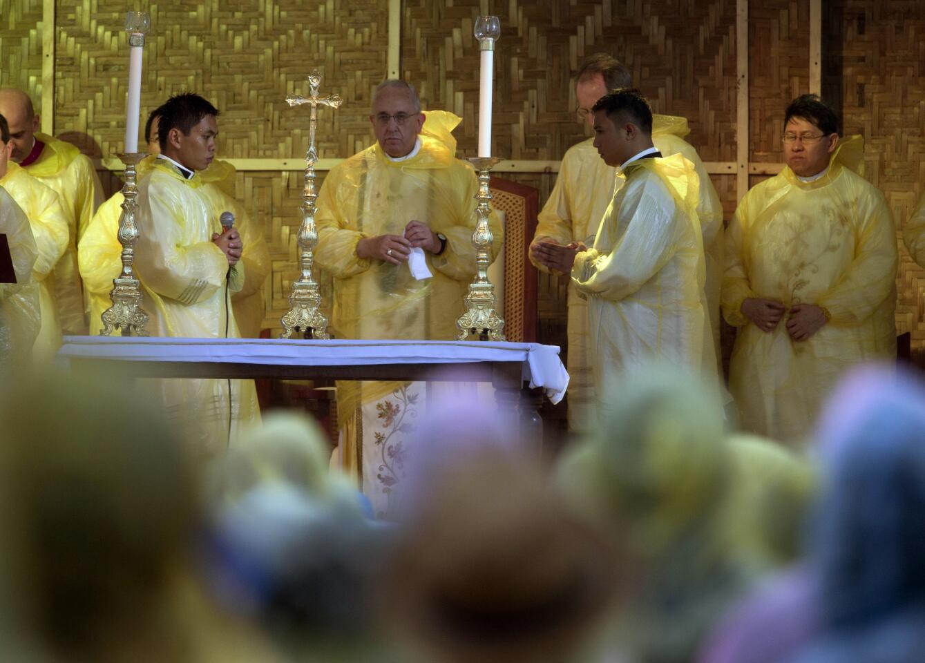 Pope Francis, center, celebrates a mass in Tacloban, Philippines. A rain-drenched but lively crowd wearing yellow and white raincoats welcomed Francis in the typhoon-ravaged city chanting "Papa Francesco, Viva il Papa!"