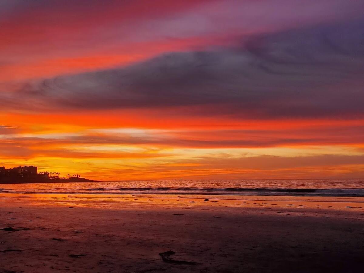 Sunset and clouds cast otherworldly hues in the sky over La Jolla Shores.