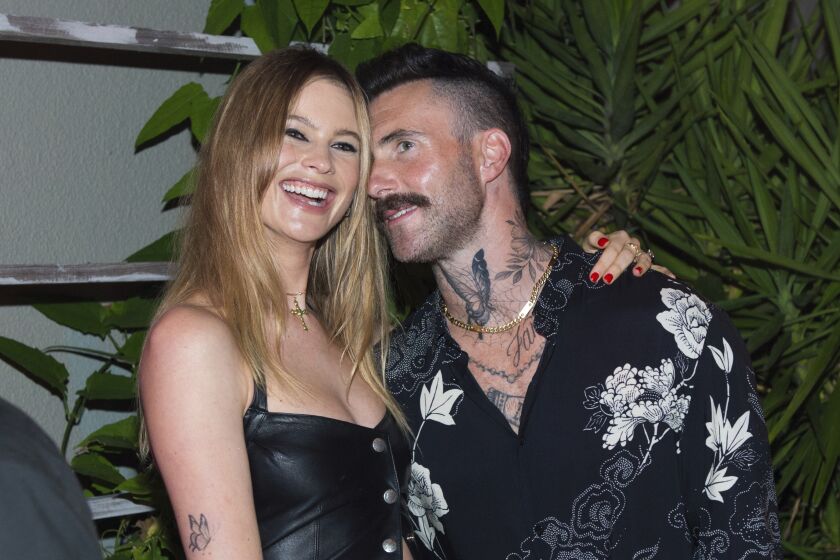 Behati Prinsloo, left, and Adam Levine attend South Beach Wine and Food Festival on Feb. 24, 2022, in Miami Beach. 
