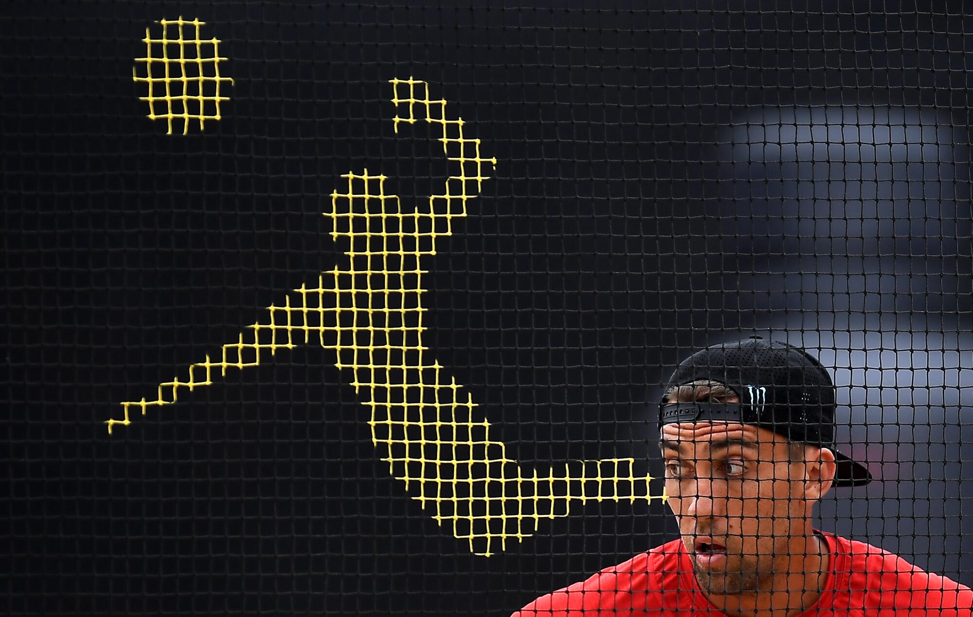 A man in a backward baseball cap in front of a pictogram depicting a volleyball player.