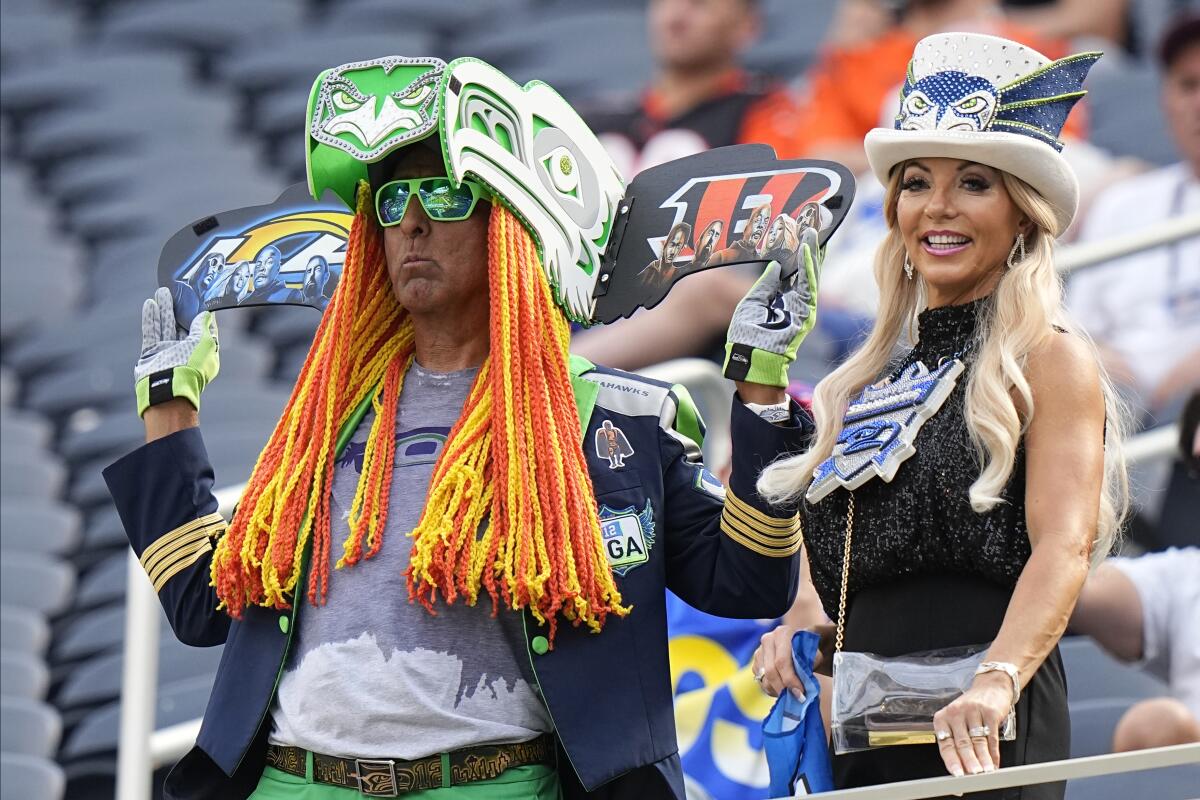 Football fans in colorful hats watch players warm up on the field before Super Bowl LVI game