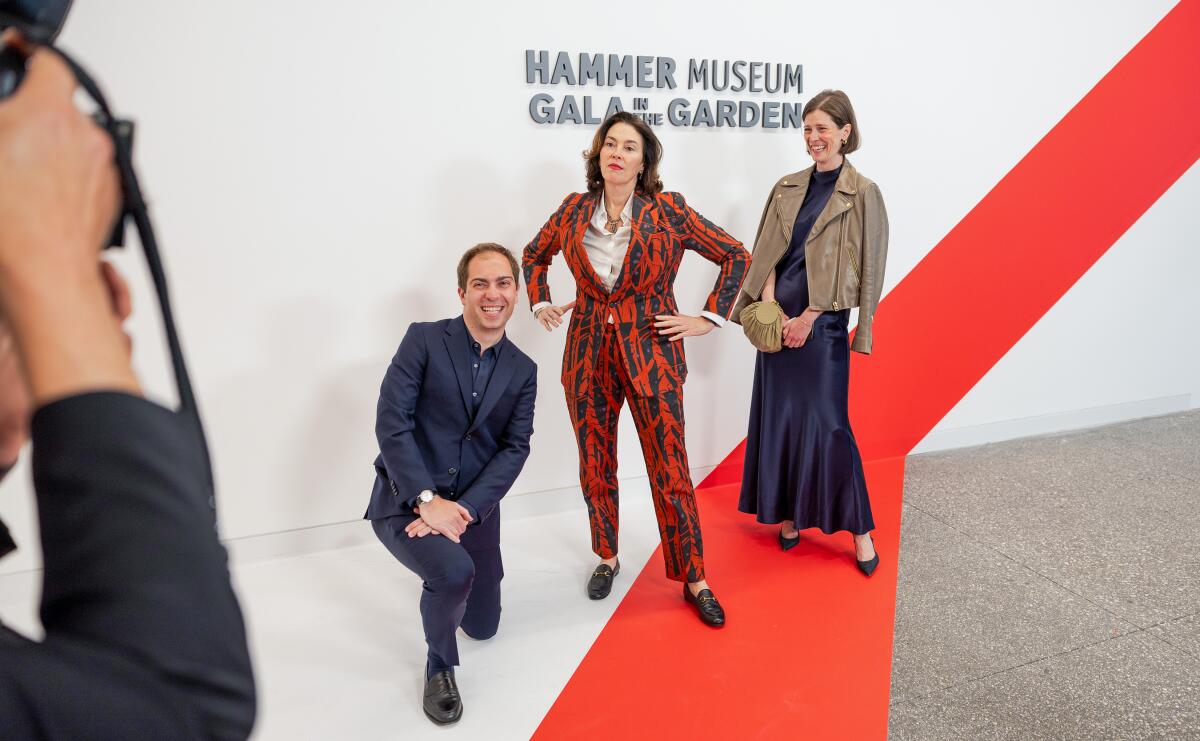 A man and two women pose for a photographer at a museum gala.