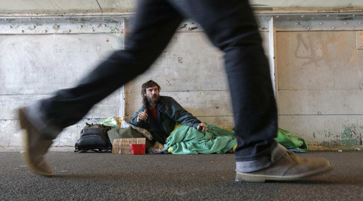 Harold McDuffie II watches pedestrians pass by as he lies in a sleeping bag on a bridge in downtown Seattle last year. The city and surrounding King County declared a state of emergency in 2015 over homelessness.