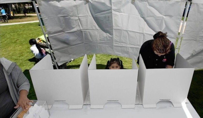 Under a white tent, parent Edith Medrano, with 3-year-old daughter Graidy, votes on who will operate 24th Street Elementary School. Parents chose a collaboration between L.A. Unified and a charter operator.