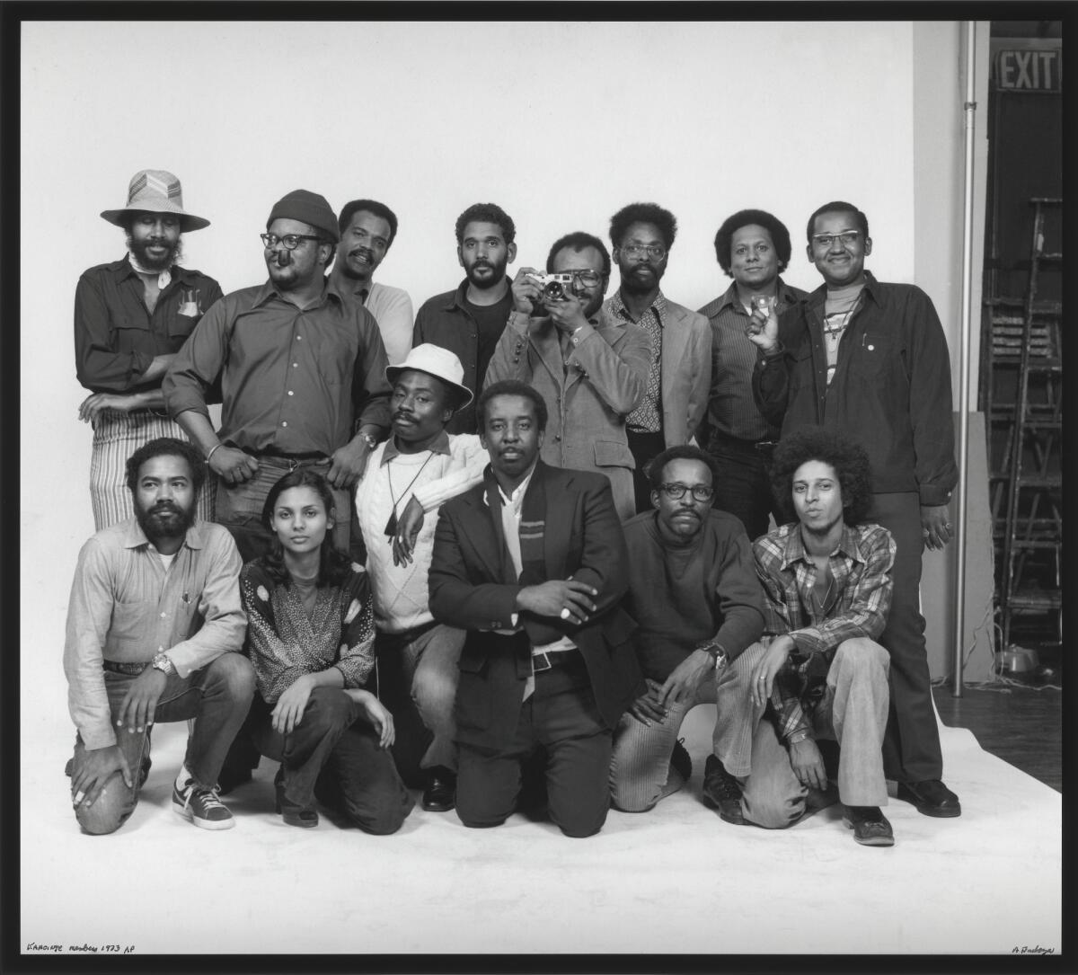 A group shot of men and women, with one man pointing a camera at the camera