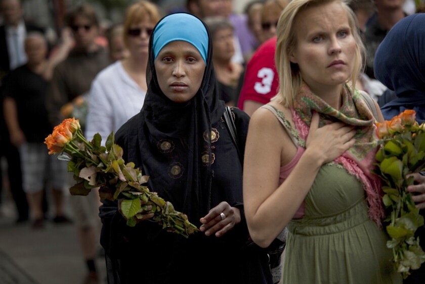 FILE - In this Sunday, July 24, 2011 file photo, women carry flowers as they arrive for a memorial service at Oslo Cathedral in the aftermath of the bombing and shooting attacks on Norway's government headquarters and a youth retreat, in Oslo. On the ten-year anniversary of Norway’s worst peacetime slaughter, survivors of Anders Breivik’s 22 July assault worry that the seam of racism that nurtured the anti-Islamic mass-murderer is re-emerging.Most of Breivik’s 77 victims were teen members of the Labor Party Youth wing - idealists enjoying their annual camping trip on the tranquil, wooded island of Utoya. Today many survivors are battling to keep their vision for their country alive. (AP Photo/Emilio Morenatti, File)