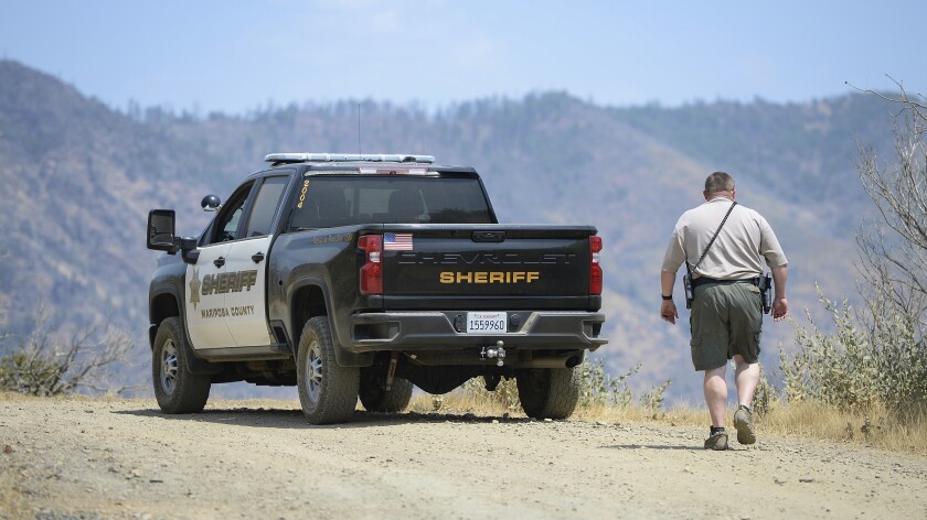 A sheriff's deputy stands near his marked pickup truck
