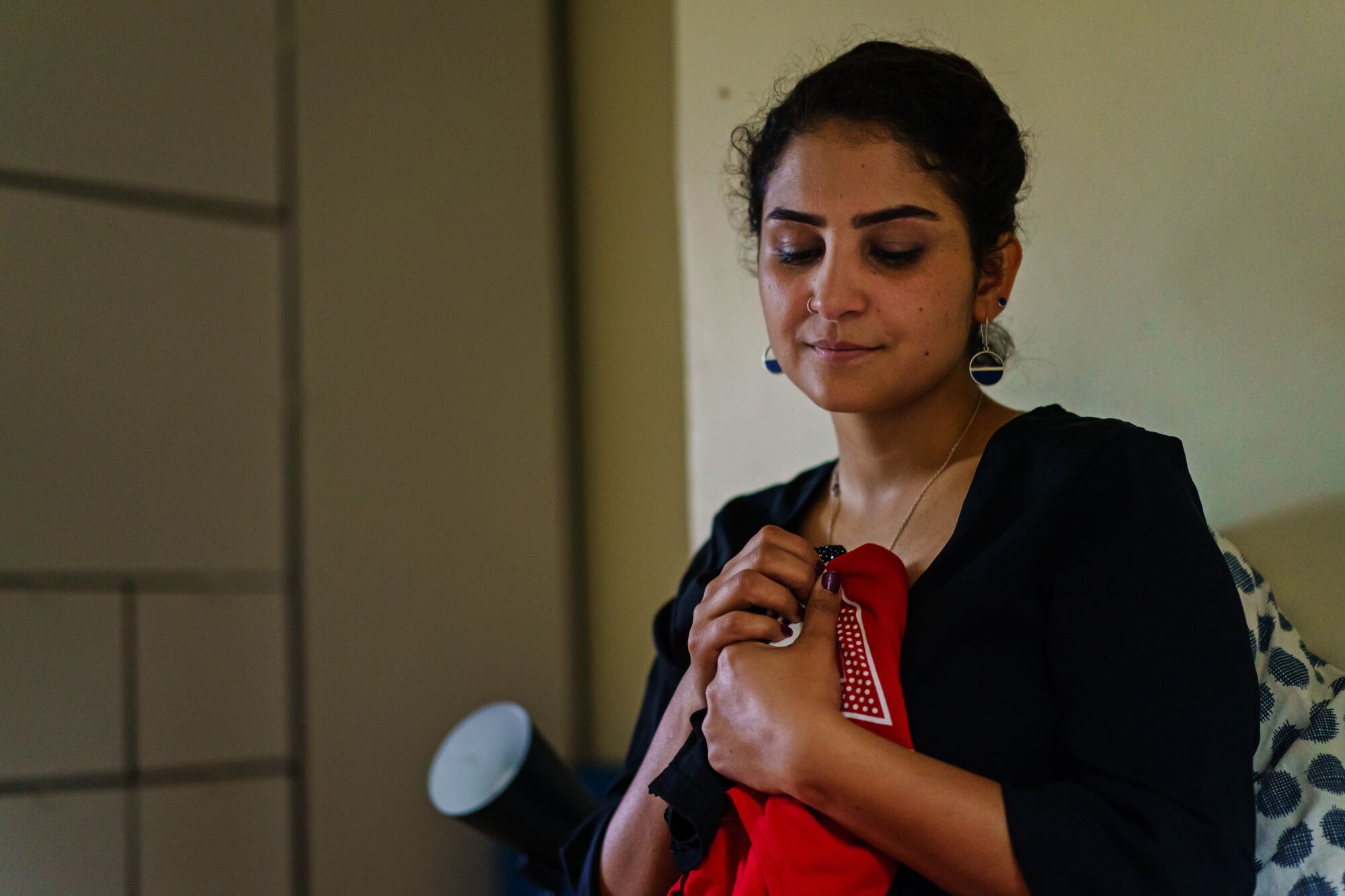 A young woman holds two tiny shirts.