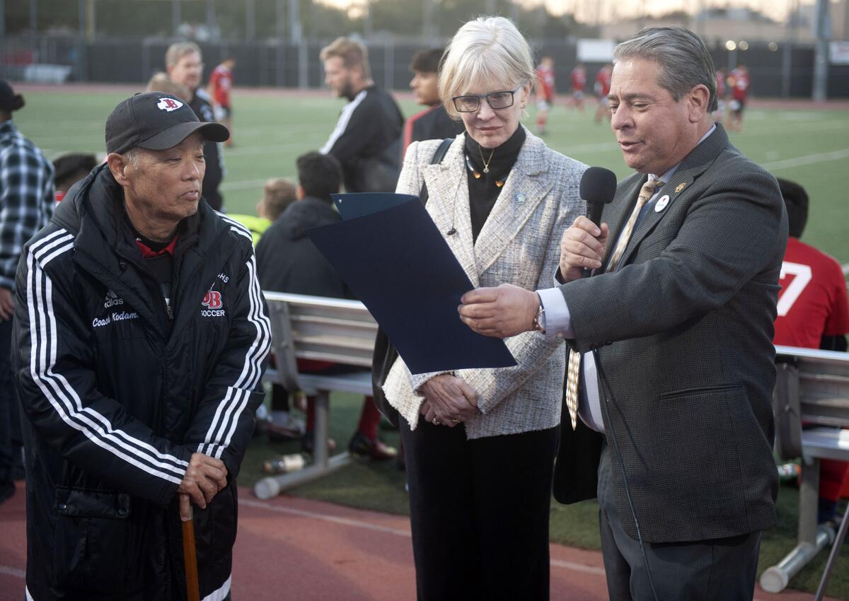 Burbank City Council Member Emily Gabriel-Luddy, center, and Vice Mayor Bob Frutos, right, read from a proclamation for former Burroughs High boys soccer coach Mike Kodama during Thursday's tribute to him. (Photo by Miguel Vasconcellos)