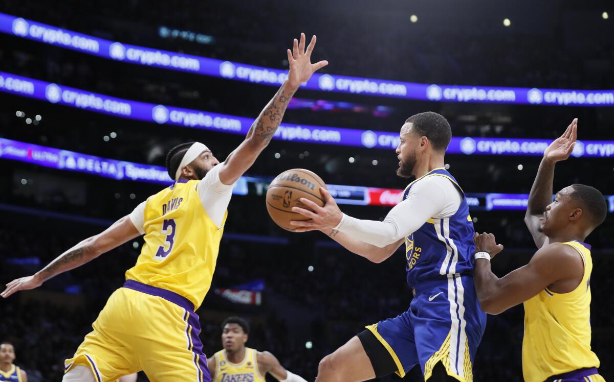Warriors guard Stephen Curry looks to pass as he's defended by Lakers forward Anthony Davis (3) guard Lonnie Walker IV.