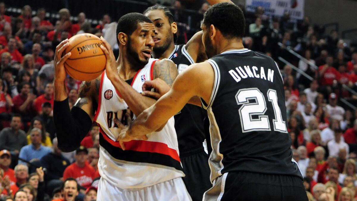 Then-Portland Trail Blazers forward LaMarcus Aldridge tries to pass between the San Antonio Spurs' Kawhi Leonard and Tim Duncan during a playoff game in May 10, 2014.