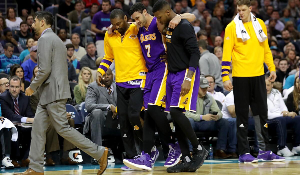 Lakers' Larry Nance Jr. is carried helped off the court after injuring his left knee against the Charlotte Hornets on Tuesday.