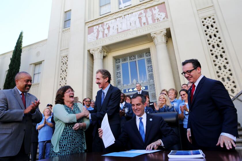 Lucy Jones, U.S. Geological Survey seismologist, second from left, celebrates with City Atty. Mike Feuer, center, as Mayor Eric Garcetti signs sweeping legislation to require earthquake retrofits on 15,000 buildings in Los Angeles on Friday.