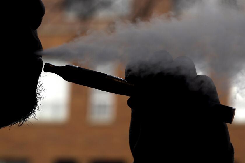 A smoker vapes with an e-cigarette. The editorial staff at Oxford Dictionaries has named "vape" the word of the year.