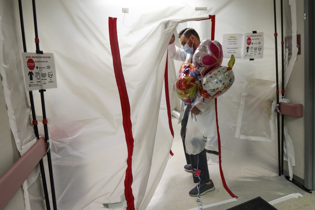 A patient's return to hospital COVID-19 unit underscores
uncertainty to come 3 Dr. Imran Siddiqui enters negative pressure enclosure with balloons for his patient.