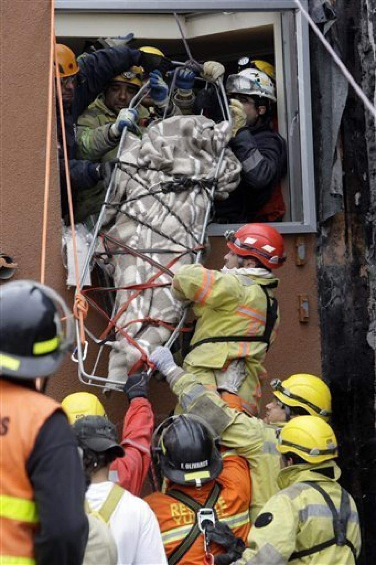 Rescue workers recover the body of an earthquake victim from a collapsed building in Concepcion, Chile, Sunday, Feb. 28, 2010. A 8.8-magnitude earthquake hit Chile early Saturday. (AP Photo/ Aliosha Marquez)